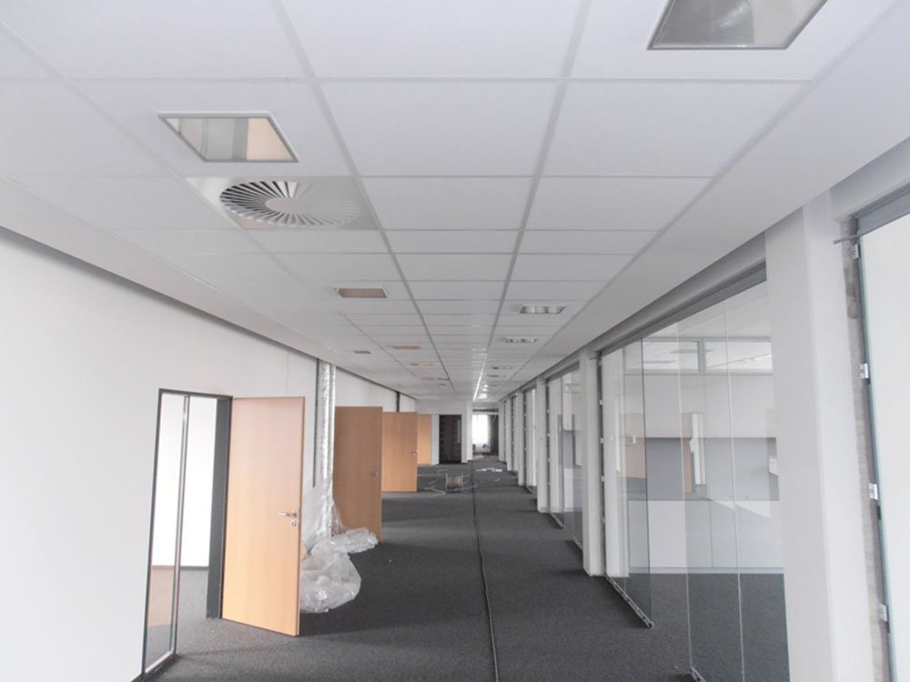 Trockenbau mit Deckensystemen und Glaswänden im Büroausbau Büroflur mit abgehängter Decke, Glaswänden und modernen Trockenbausystemen während des Innenausbaus